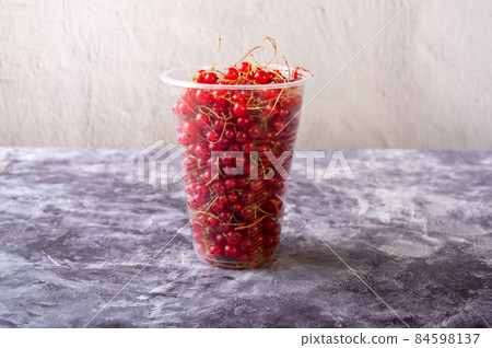 Red currants in a plastic glass. Homemade currants in a glass. Currants on the windscreen. 84598137