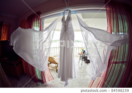 Wedding dress at the hotel on the background of the pool, ocean and mountains Wedding dress at the hotel on the background of the pool, ocean and mountains 84598239