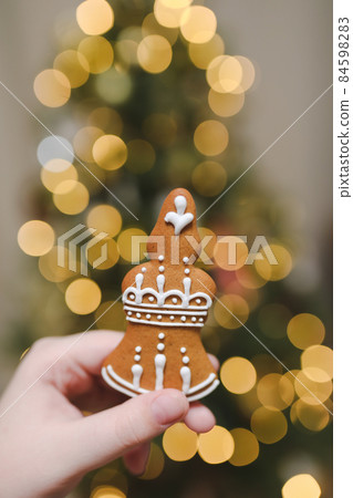 Hand holding gingerbread on the background of the Christmas tree. Holiday, Christmas and New Year celebration concept Hand holding gingerbread on the background of the Christmas tree. Holiday, Christmas and New Year celebration concept 84598283