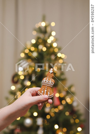 Hand holding gingerbread on the background of the Christmas tree. Holiday, Christmas and New Year celebration concept 84598287