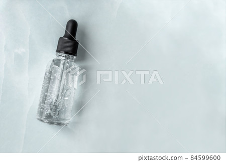 Transparent glass dropper bottle with air bubbles on marble background. Pipette with fluid hyaluronic acid, serum, retinol or oil. Cosmetics and healthcare concept. Flat lay. Luxury beauty product 84599600