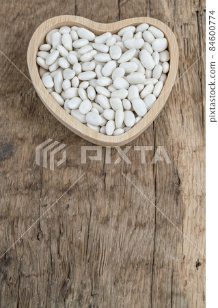 white haricot beans in heart shaped plate on wooden background 84600774