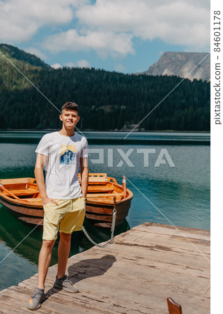 Young man looking at Black Lake, Durmitor National Park, Zabljak, Montenegro. Hipster traveler enjoying view of Black Lake Young man looking at Black Lake, Durmitor National Park, Zabljak, Montenegro. Hipster traveler enjoying view of Black Lake 84601178