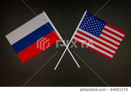 Russia flag and USA flag crossed with each other on the black background. Russia vs USA. Meeting between the presidents of the Russia and United States. Isolated. Top view Russia flag and USA flag crossed with each other on the black background. Russia vs USA. Meeting between the presidents of the Russia and United States. Isolated. Top view 84601570