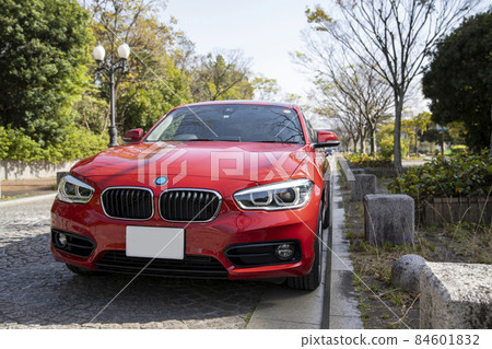 在公園裡拍攝的一輛紅色汽車，周圍環繞著新鮮的綠色植物 84601832