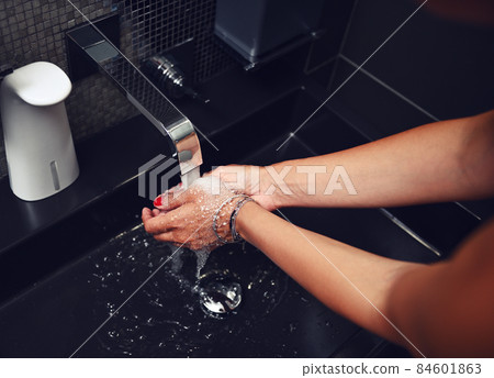 Overhead view of unrecognizable woman washing hands under a jet of running water. Close-up, cropped image Overhead view of unrecognizable woman washing hands under a jet of running water. Close-up, cropped image 84601863