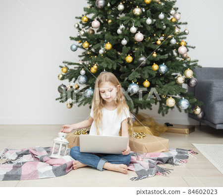 Little Girl plays near the Christmas tree. 84602023