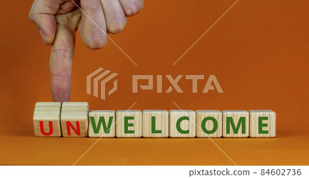Welcome or unwelcome symbol. Businessman turns wooden cubes and changes the word unwelcome to welcome. Beautiful orange table, orange background. Welcome or unwelcome and business concept. Copy space. Welcome or unwelcome symbol. Businessman turns wooden cubes and changes the word unwelcome to welcome. Beautiful orange table, orange background. Welcome or unwelcome and business concept. Copy space. 84602736