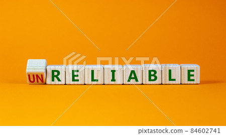 Unreliable or reliable symbol. Turned wooden cubes and changed the word unreliable to reliable. Beautiful orange background, copy space. Business and unreliable or reliable concept. 84602741
