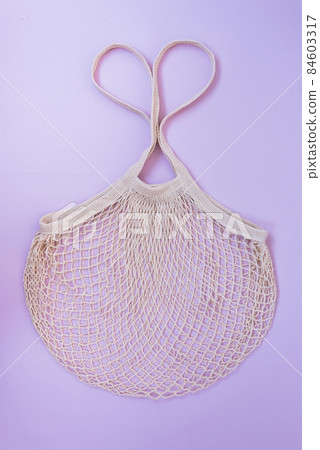 Mesh Shopping Bag. The handles of the bag are folded in the shape of a heart. The concept of love and care for the environment. Sustainable shopping. Reuse. Shopping for Valentine's Day 84603317