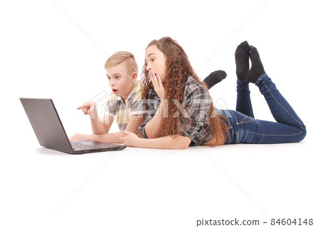 Boy and girl using a laptop lying on the floor Boy and girl using a laptop lying on the floor 84604148