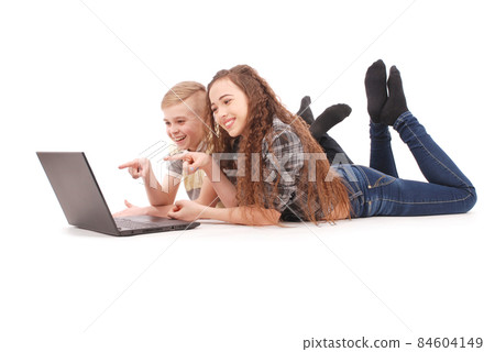 Boy and girl using a laptop lying on the floor Boy and girl using a laptop lying on the floor 84604149