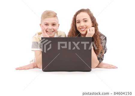 Boy and girl using a laptop lying on the floor 84604150