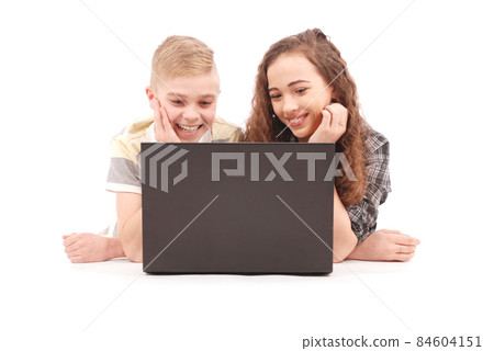 Boy and girl using a laptop lying on the floor Boy and girl using a laptop lying on the floor 84604151