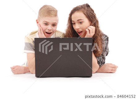 Boy and girl using a laptop lying on the floor Boy and girl using a laptop lying on the floor 84604152