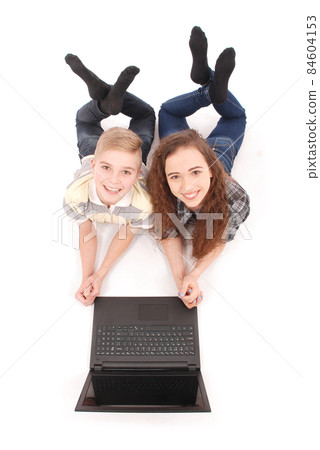 Boy and girl using a laptop lying on the floor Boy and girl using a laptop lying on the floor 84604153