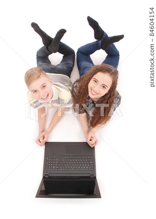 Boy and girl using a laptop lying on the floor Boy and girl using a laptop lying on the floor 84604154