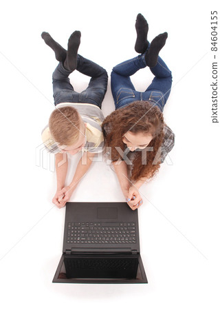 Boy and girl using a laptop lying on the floor Boy and girl using a laptop lying on the floor 84604155