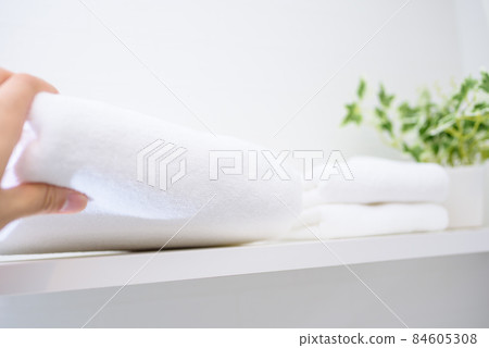 A man's hand taking a towel on the shelf 84605308