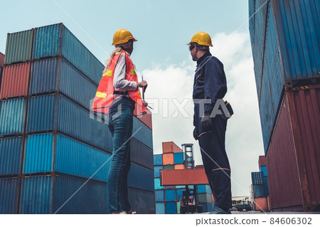 Industrial worker works with co-worker at overseas shipping container yard 84606302
