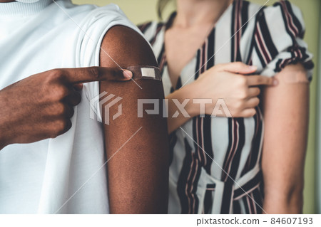 Diverse group of people showing COVID-19 vaccine bandage merrily 84607193