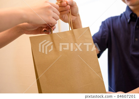 一名男性送貨員通過送餐服務提供食物，一名女性接受食物。 84607201
