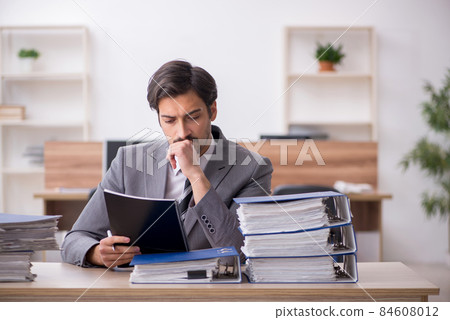 Young male employee unhappy with excessive work in the office Young male employee unhappy with excessive work in the office 84608012