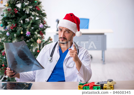 Young male doctor celebrating Christmas at the hospital Young male doctor celebrating Christmas at the hospital 84608345