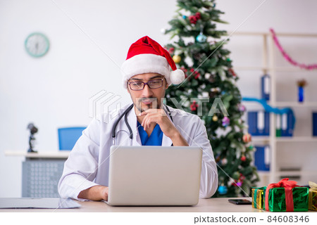 Young male doctor celebrating Christmas at the hospital Young male doctor celebrating Christmas at the hospital 84608346