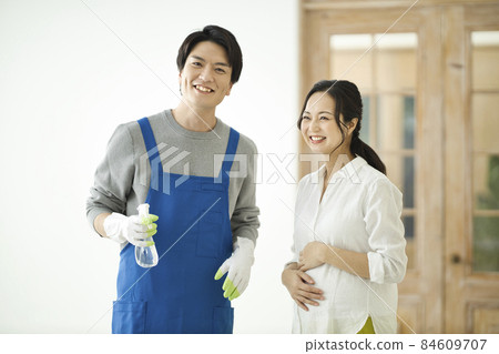一個打掃衛生的男人和一個微笑著看著的孕婦 84609707