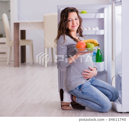 Pregnant woman near fridge looking for food and snacks 84611740