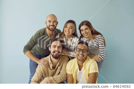 Group portrait of five happy, smiling mixed race multi ethnic friends. Team of 5 cheerful young diverse people with toothy smiles having photoshoot and looking at camera against blue studio background Group portrait of five happy, smiling mixed race multi ethnic friends. Team of 5 cheerful young diverse people with toothy smiles having photoshoot and looking at camera against blue studio background 84614092