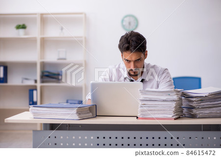 Young male employee and too much work in the office 84615472