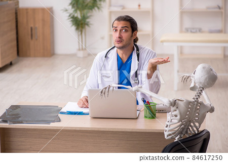 Young male doctor and skeleton patient in the clinic 84617250