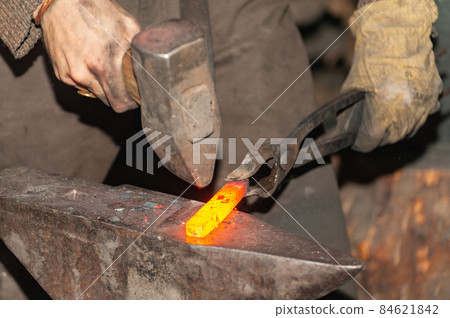 Detail shot of hammer forging hot iron at anvil 84621842