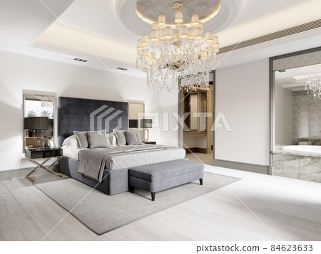 Luxurious bedroom with white walls and a gray fabric bed with black bedside tables and lamps and a large luminous crystal chandelier. 84623633