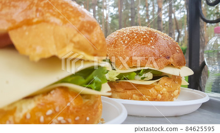 Close-up of two large DIY hamburgers in the park on a barbecue, rest and cooking on a picnic in the summer, food, delicious, bright colors. Unhealthy food concept. Fast food. Close-up of two large DIY hamburgers in the park on a barbecue, rest and cooking on a picnic in the summer, food, delicious, bright colors. Unhealthy food concept. Fast food. 84625595