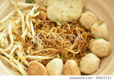 dry Chinese yellow egg noodles dressing black sweet soy sauce with pork meatball and bean sprout in soup on bowl 84625715