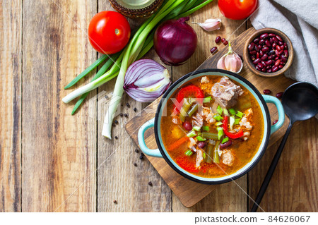 Traditional English thick soup with beef, beans and vegetables on a wooden table. Hot dinner or lunch. Top view flat lay. Copy space. Traditional English thick soup with beef, beans and vegetables on a wooden table. Hot dinner or lunch. Top view flat lay. Copy space. 84626067