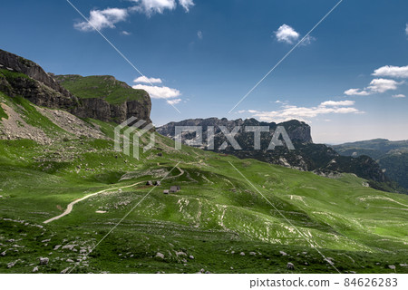 Amaizing view on Durmitor mountains, National Park, Mediterranean, Montenegro, Balkans, Europe. Bright summer view from Sedlo pass. The road near the house in the mountains. Amaizing view on Durmitor mountains, National Park, Mediterranean, Montenegro, Balkans, Europe. Bright summer view from Sedlo pass. The road near the house in the mountains. 84626283