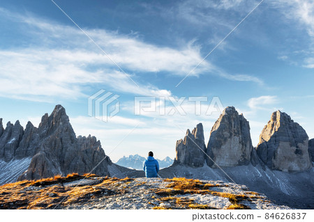 Tourist in blue jacket at Three Peaks of Lavaredo track on autumn season Tourist in blue jacket at Three Peaks of Lavaredo track on autumn season 84626837