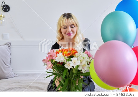 Portrait of birthday girl teenager with bouquet of flowers and balloons at home 84628162