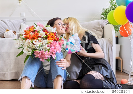 Mom congratulating her teenage daughter with gift flowers, at home in room Mom congratulating her teenage daughter with gift flowers, at home in room 84628164