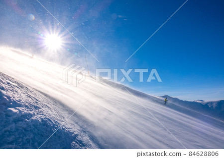 Lone Skier on a Sunny Slope and Blizzard Lone Skier on a Sunny Slope and Blizzard 84628806