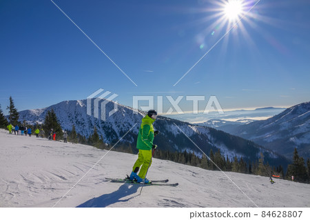 Skier in Yellow Ski Suit on a Sunny Ski Slope Skier in Yellow Ski Suit on a Sunny Ski Slope 84628807