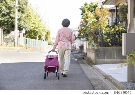 一位老婦人背著購物車走路的背影 84629045
