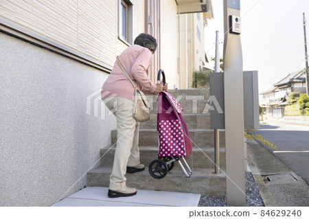 Senior woman going up the stairs with a shopping carry Senior woman going up the stairs with a shopping carry 84629240