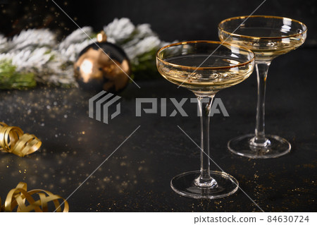 Festive New Year champagne flutes and Christmas gold baubles on black background. 84630724