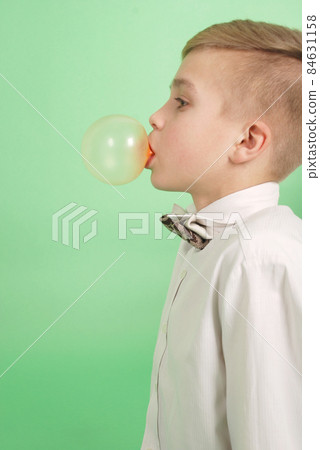 Boy blowing a bubblegum bubble Boy blowing a bubblegum bubble 84631158