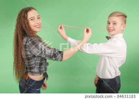 Young boy and girl stretching from chewing gum which he carries in his mouth 84631183